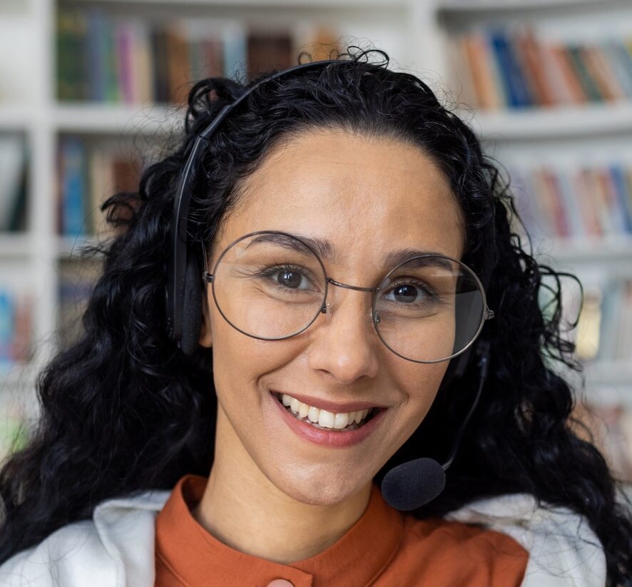 Portrait of attractive young woman with curly hair wearing eyeglasses and casual outfit on blurred